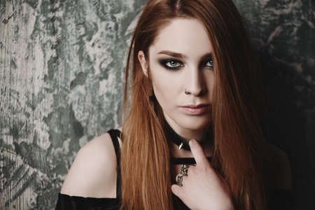 Close-up portrait of a beautiful hipster woman with piercings in the nose over grunge background. Beauty, make-up. Fashion. Gothic style. の写真素材