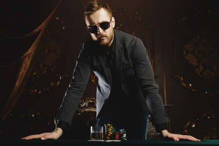 Rich gambler man with the cards and chips in casino. Gambling, playing cards and roulette.の写真素材