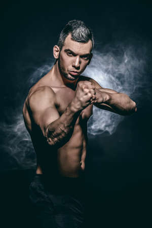 Athlete stands in the fighting stance, ready to strike with his fist. Healthy lifestyle.の写真素材