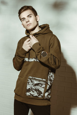 Portrait of a teenage boy standing by a white brick wall. Studio shot. Teen fashion.