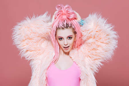 Stylish girl with pink dreadlocks posing in bright clothes on a pink background. Beauty, fashion.の写真素材
