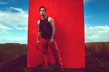 Fashion shot of a professional handsome male model posing in a wheat field. Full length portrait. 