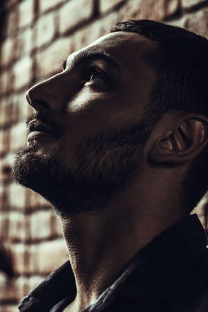 Close-up portrait of a handsome brunet man over brick wall background. Men's beauty, fashion. Men's barbershop, Hairstyle.の写真素材