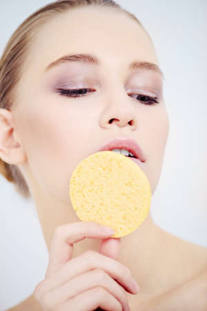 Close-up portrait of a beautiful girl with healthy shiny skin holding a sponge. Beauty, fashion. Skincare, healthcare. Spa for women.の写真素材