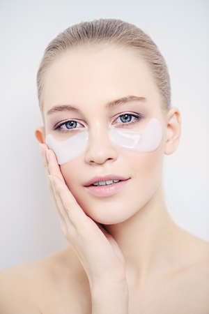 Close-up portrait of a beautiful young woman with collagen pads under her eyes. Spa, eye skin care.の写真素材