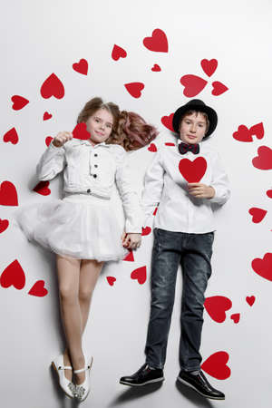 Happy pre-teen boy and girl  are posing surrounded by hearts. Friendship. First love. Valentine's Day. の写真素材