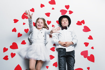 Happy pre-teen boy and girl  are posing surrounded by hearts. Friendship. First love. Valentine's...