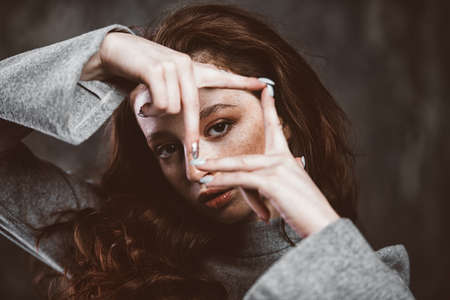 Modern  fifteen-year-old girl with long curly red hair posing over grunge background. Beauty, fashion.の写真素材