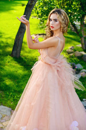 Charming bride girl in a beautiful wedding dress  with lush skirt posing in a summer park. の写真素材