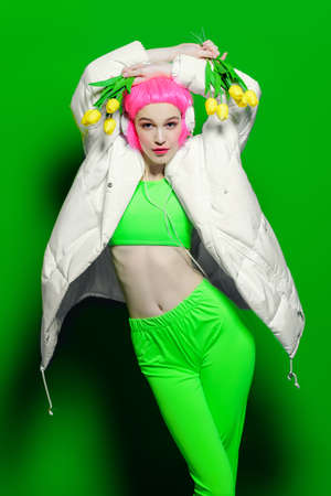 Trendy girl with pink hair wearing bright stylish clothes. Green background. Beauty, fashion, youth style.の写真素材