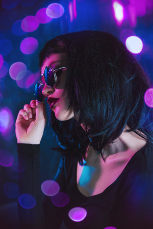 Close-up portrait of a beautiful blonde woman in stylish sunglasses over dark background. Beauty,...