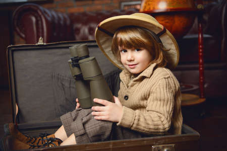 Cute child boy in a travel suitcase playing at home. Childhood. Fantasy, imagination. の写真素材