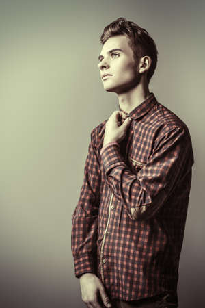 Portrait of a handsome teenage boy in a plaid shirt over gray background. Studio shot. Teen fashion.の写真素材