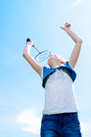 Happy joyful girl is playing badminton. Summer outdoor activities. Sky background.の写真素材