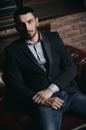 Portrait of a sexy handsome man on a leather sofa. Fashion shot. Men's beauty, fashion. Men's...