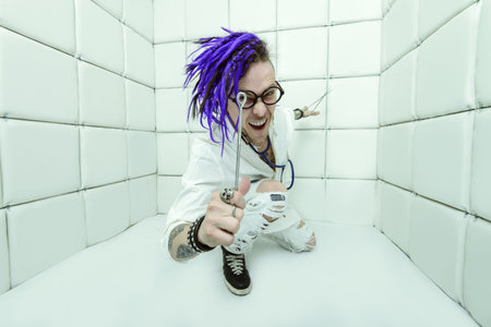 Portrait of a cheerful crazy doctor in a psychiatric hospital with surgical instruments. Concept of...