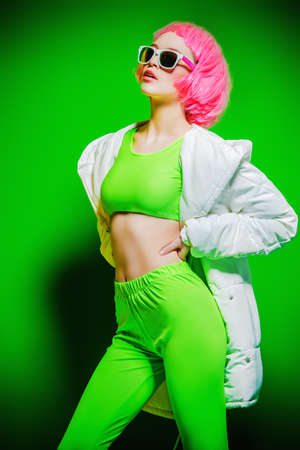 Trendy girl with pink hair wearing bright stylish clothes. Green background. Beauty, fashion, youth style.の写真素材