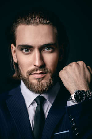 Fashion shot. Handsome young man posing in elegant suit and white shirt over black background. Men's beauty, fashion.の写真素材