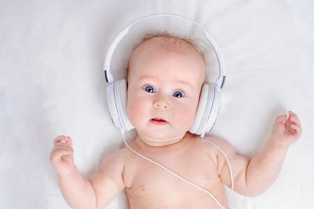 Cute three-month-old baby listening to music in headphones.の写真素材