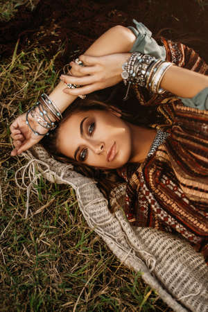 Beautiful hippie girl lying in a grass. Modern boho style. Beauty, fashion,の写真素材