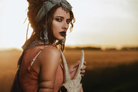 Magnificent gypsy fortune teller with a skull in the rays of the sunset.の写真素材