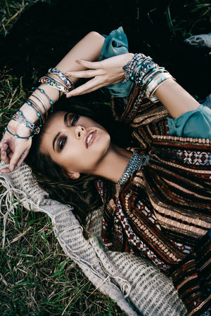 Beautiful hippie girl lying in a grass. Modern boho style. Beauty, fashion,