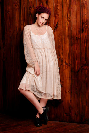 Pretty young woman in casual clothes posing by a wooden wall. Youth style, fashion. Full length portrait.の写真素材