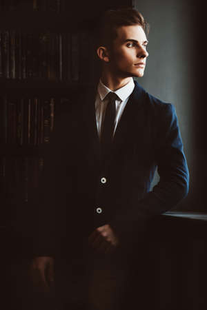 Intelligent student boy in elegant clothes standing in the library. Fashion. Educational concept.の写真素材