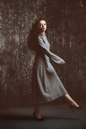 Modern  fifteen-year-old girl with long curly red hair is dancing in the studio. Beauty, fashion. Vogue dance.の写真素材