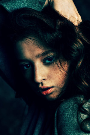 Close-up portrait of a  fifteen-year-old girl with long curly red hair over grunge background....