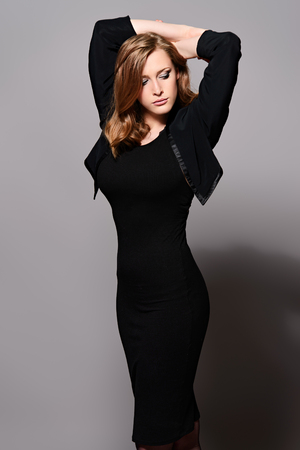 Elegant young woman wearing black fitting dress and jacket. Beauty, fashion concept. Studio shot.の写真素材