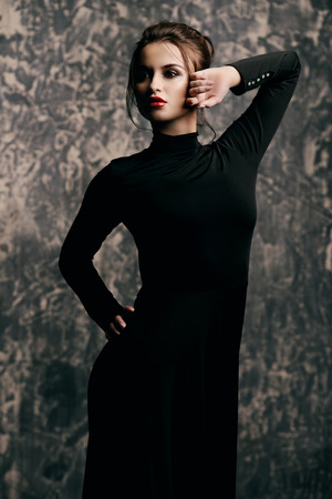 Elegant young woman wearing black fitting long dress. Beauty, fashion concept. Studio shot.の写真素材