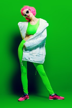 Full length portrait of a trendy girl with pink hair wearing bright stylish clothes. Green background. Beauty, fashion, youth style.の写真素材