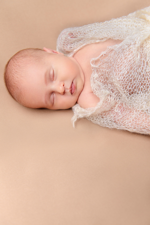 Close-up portrait of a lovely sleeping newborn baby wrapped in knitted blanket. Baby care, Healthcare.の写真素材