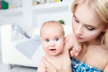 Portrait of a happy young mother with her small baby at home. Family concept. Healthcare, pediatrics.の写真素材