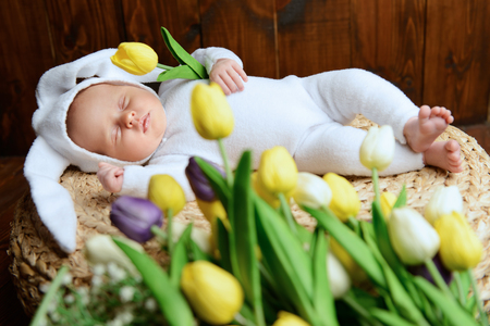 Cute newborn baby lies on a wooden background, dressed in rabbit costume. Easter holiday. Scenery in the rustic style.の写真素材