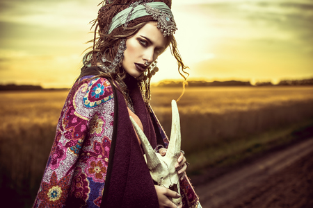 Magnificent gypsy fortune teller with a skull in the rays of the sunset.の写真素材