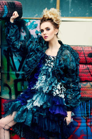 Modern young woman fluffy dress and jacket posing on street to the outskirts of the city. Beauty, street fashion.の写真素材