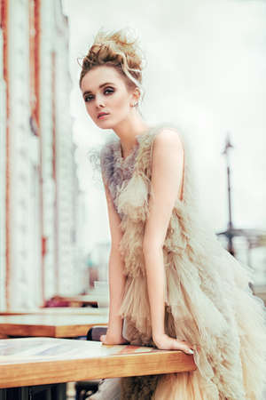 Beautiful young woman in an elegant fluffy dress posing on street. Beauty, street fashion.の写真素材