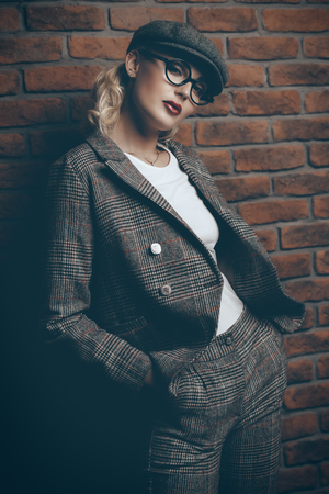 Portrait of a sexual young woman wearing checkered suit, cap and glasses.の写真素材