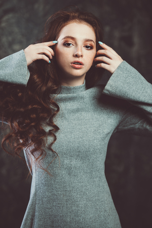 Portrait of a  fifteen-year-old girl with long curly red hair over grunge background. Beauty, fashion.の写真素材