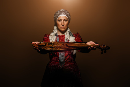 Elderly native woman in a national costume plays the ancient violin.の写真素材