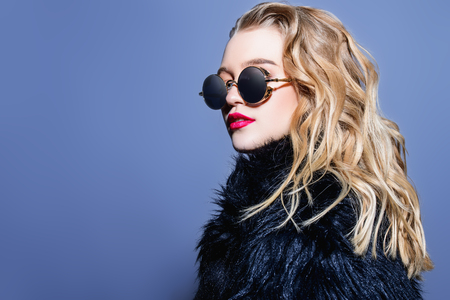 Attractive young woman wearing black sunglasses and fur coat. Studio shot. Beauty, fashion concept.の写真素材