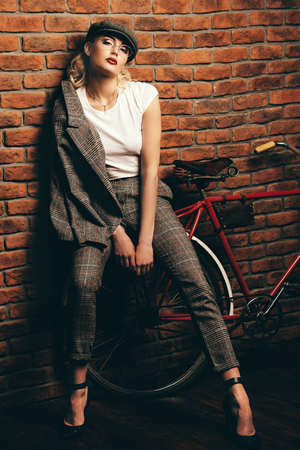 Portrait of a sexual young woman wearing checkered suit, cap and glasses. Beautiful smart girl. Beauty, fashion.の写真素材