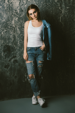 Portrait of a beautiful girl in casual clothes over grunge background. Beauty, fashion concept. Studio shot. Full length portrait.の写真素材