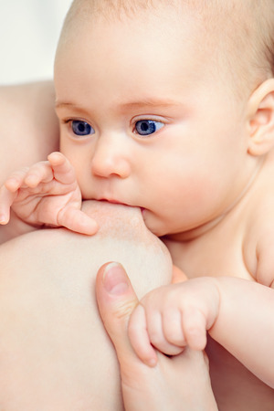 Close-up portrait of a newborn baby sucking a mother's breast. Natural feeding for babies. Baby care. Healthcare.の写真素材