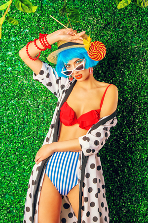 Portrait of a bright fashion model with blue hair wearing swimsuit over lawny background. Beauty, fashion concept.  Pin-up style.の写真素材