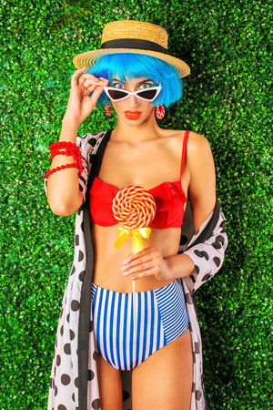 Portrait of a bright fashion model with blue hair wearing swimsuit over lawny background. Beauty, fashion concept.  Pin-up style.の写真素材