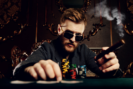A wealthy mature man playing poker in a casino. Gambling, playing cards and roulette.の写真素材