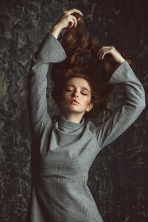 Close-up portrait of a  fifteen-year-old girl with long curly red hair over grunge background. Beauty, fashion.の写真素材